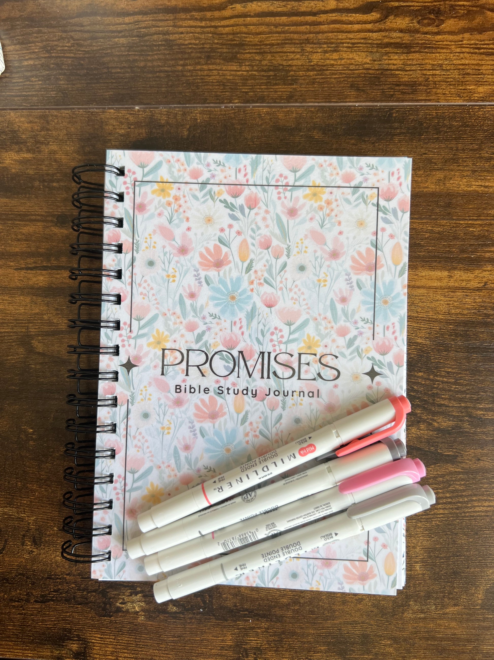 Spiral-bound Bible study journal titled "Promises of God" by Sons & Daughters, featuring lined pages and spiritual prompts.