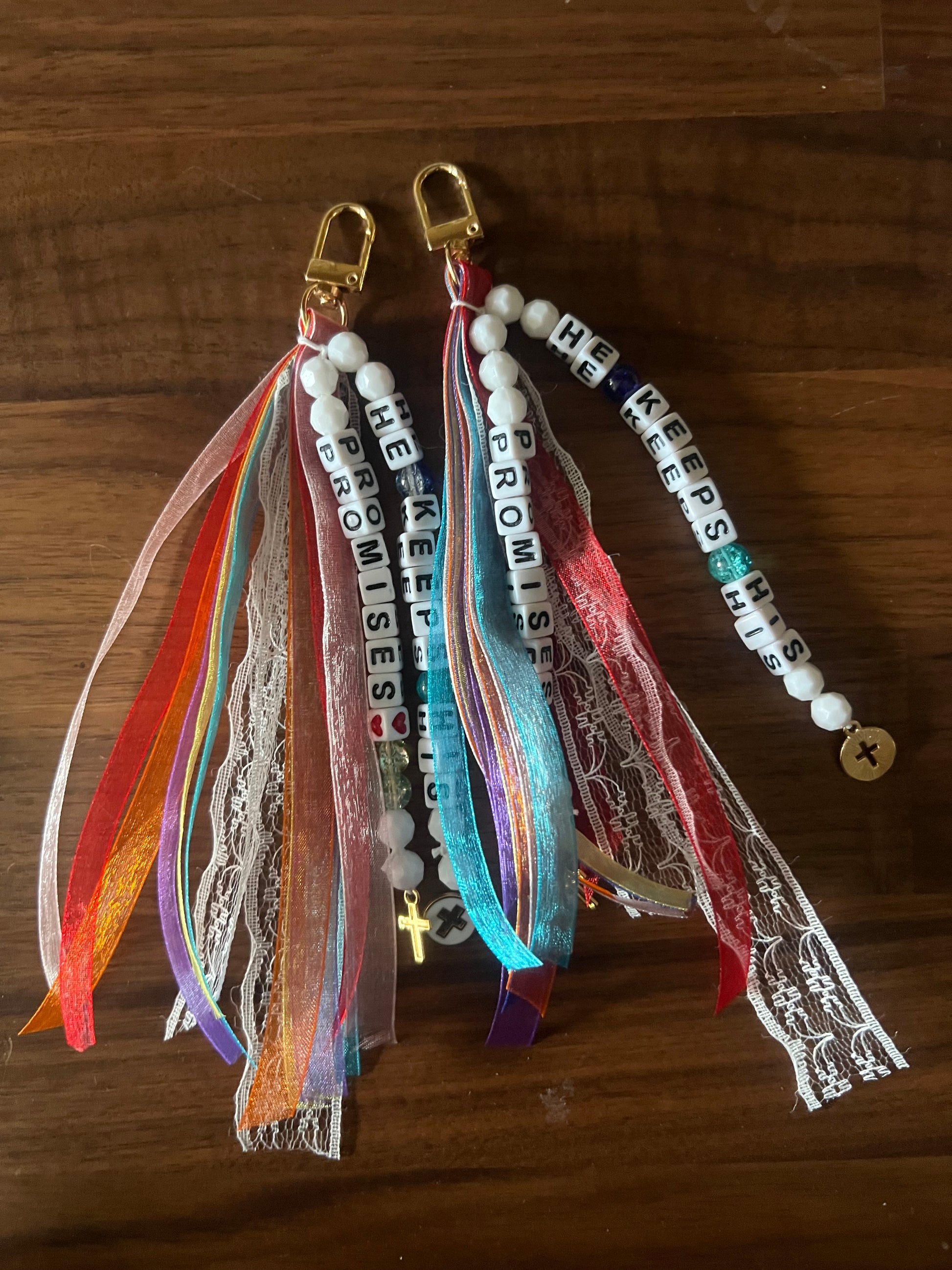 Colorful Sons & Daughters "He Keeps His Promises" keychain with engraved message and metal ring, designed for keys or accessories.