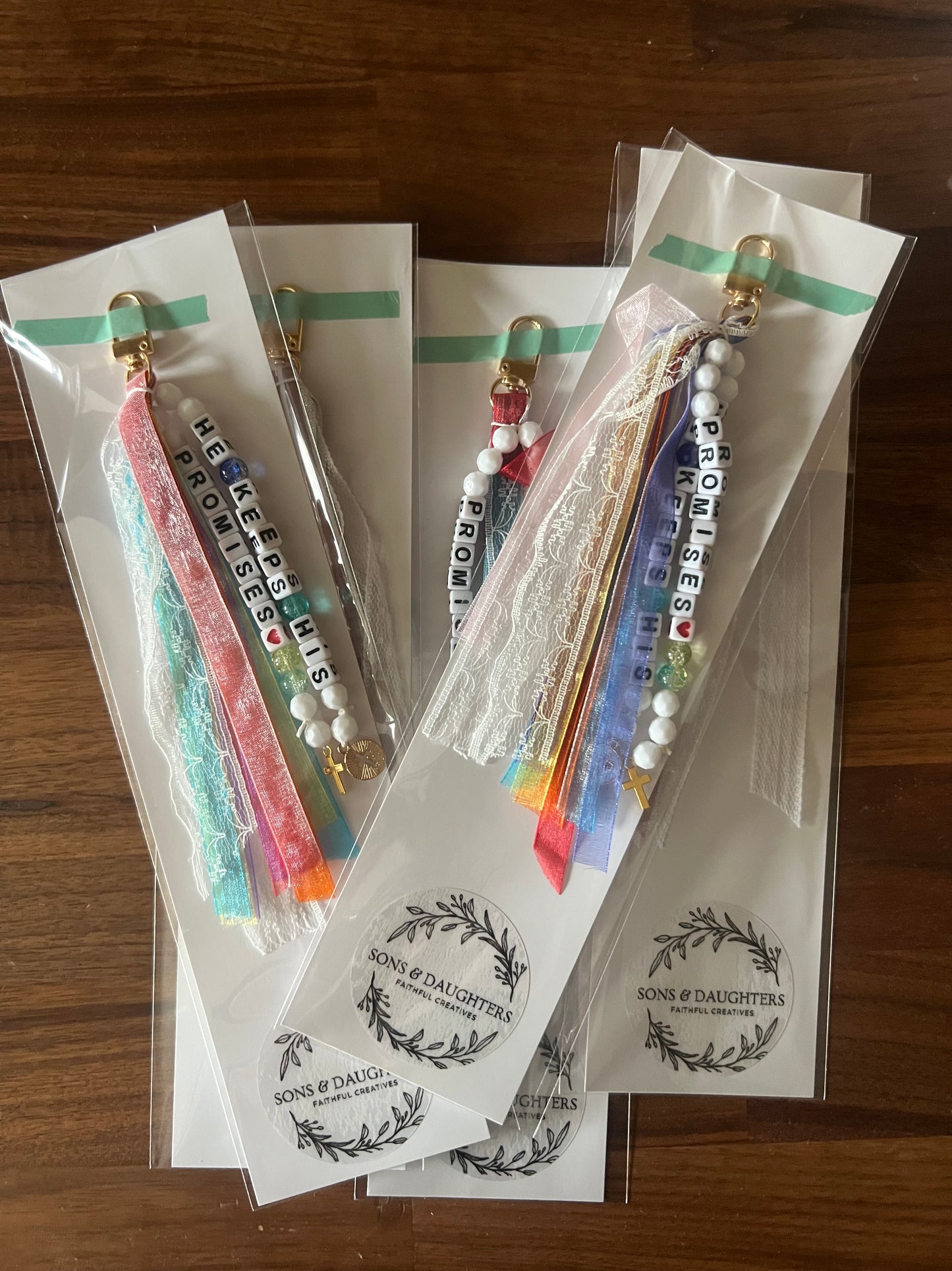 Colorful Sons & Daughters "He Keeps His Promises" keychain with engraved message on a metal keyring, vibrant and durable design.
