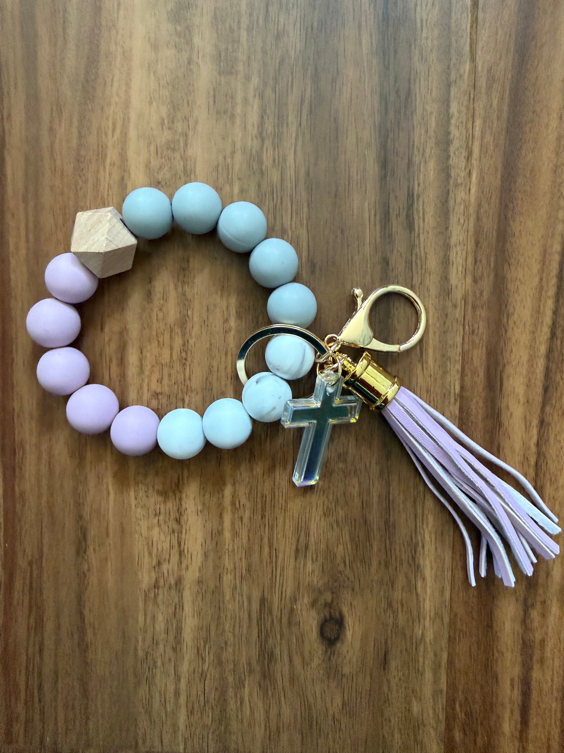 Silicone cross bracelet keychain from Sons & Daughters, colorful accessories with a cross design, on a plain background.