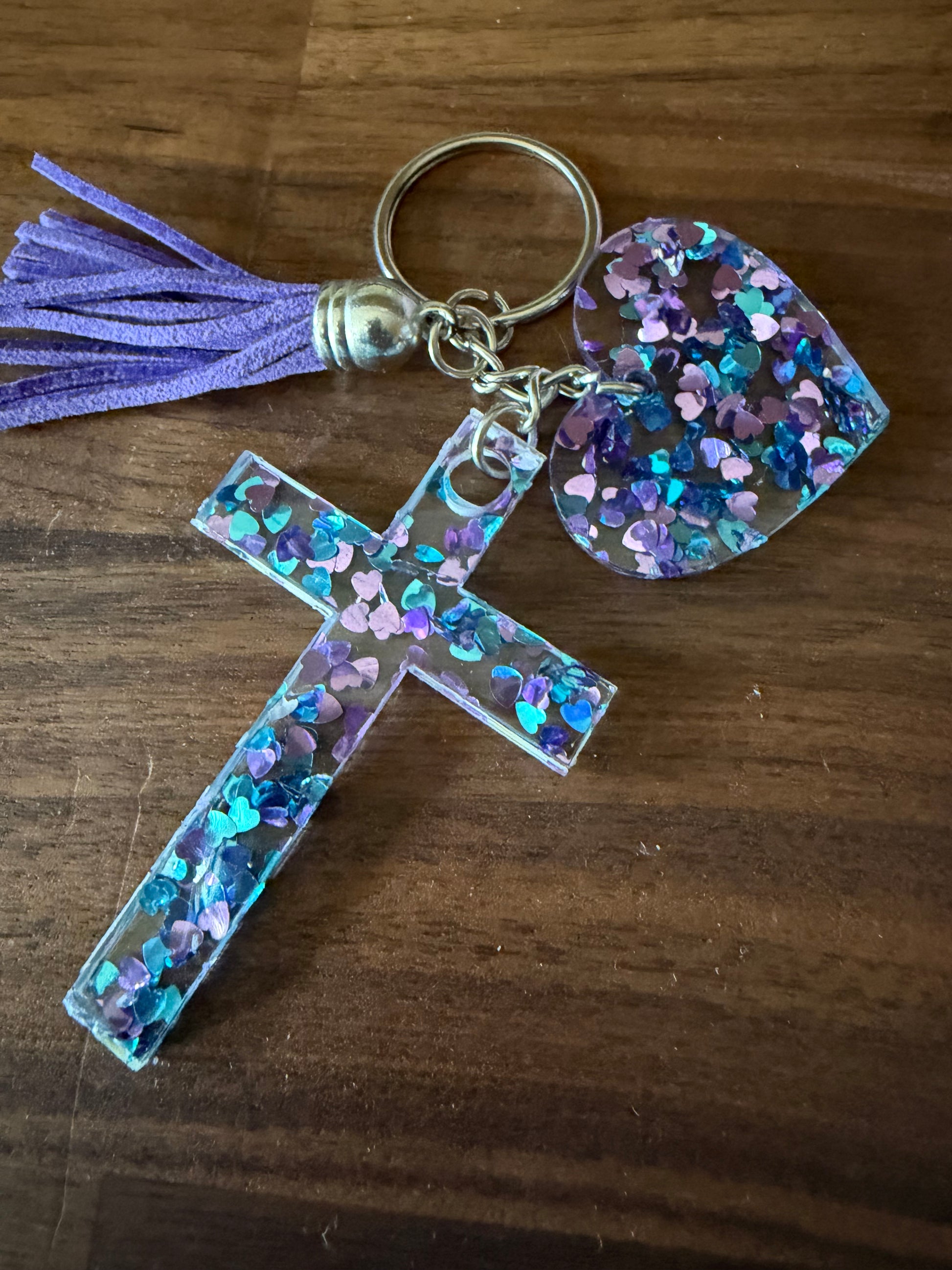 Acrylic glitter keychains featuring a cross and heart design from Sons & Daughters accessories collection.