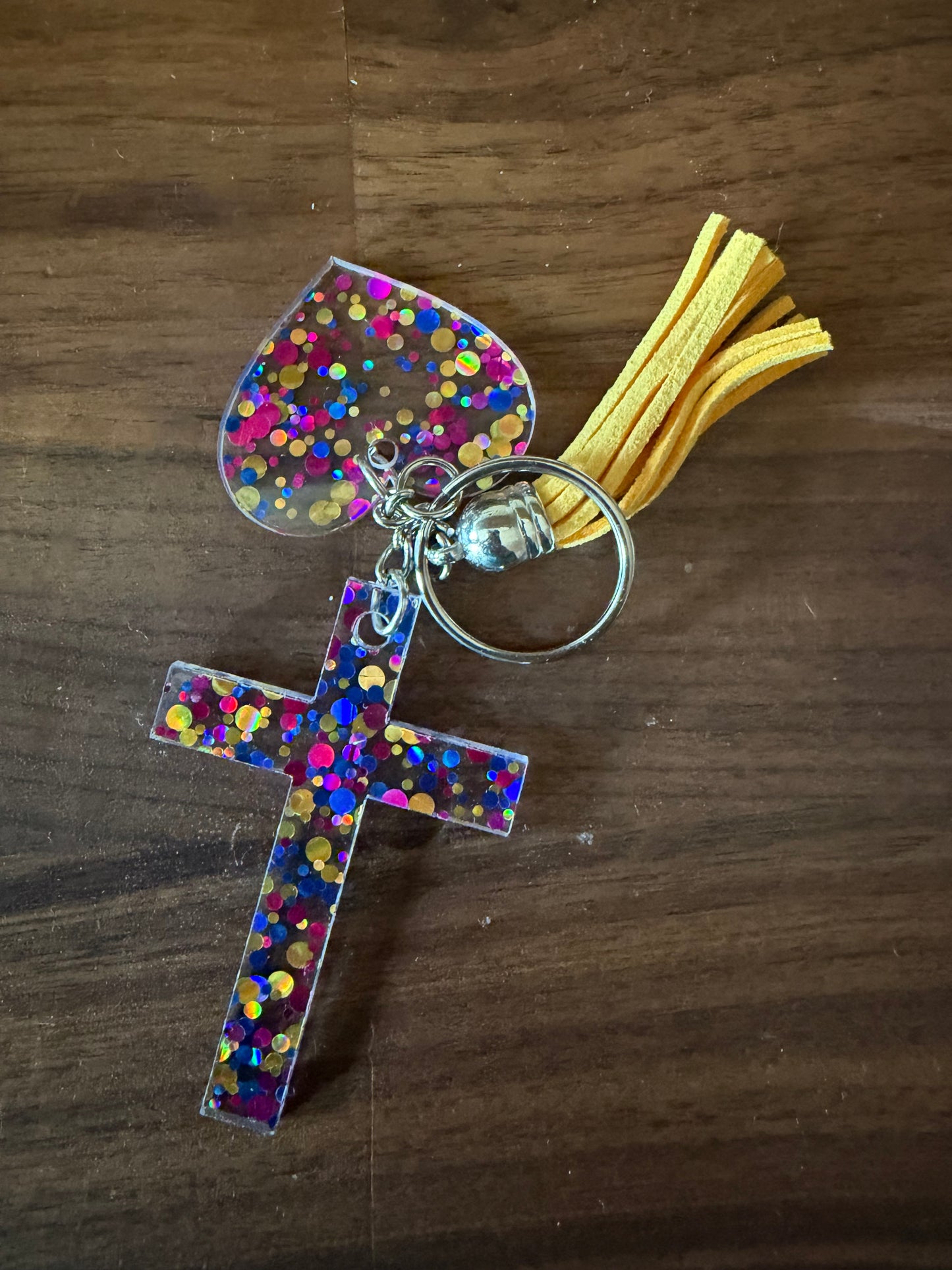 Glitter acrylic cross and heart keychains from Sons & Daughters, colorful accessories with shiny, reflective surfaces.