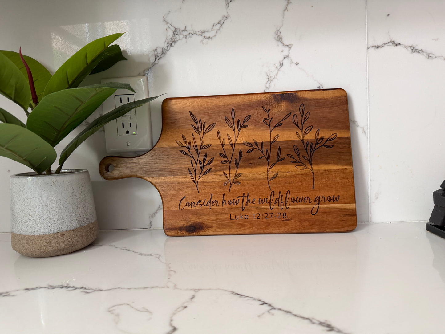Faith inspired engraved acacia wood cutting board with scripture Luke 12:27-28, perfect for Christian kitchen decor and serving.
