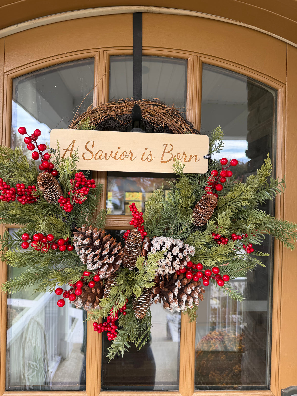 A Savior Is Born door wreath by Sons & Daughters with festive Christian holiday design