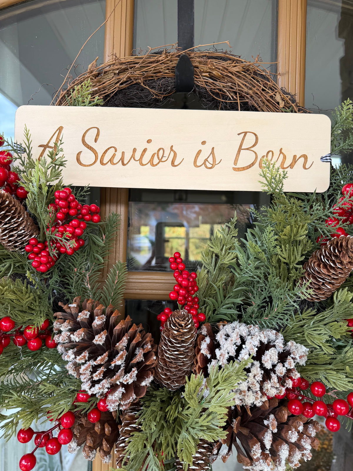 Sons & Daughters “A Savior Is Born” Christmas door wreath with festive seasonal greenery